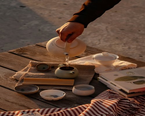 A person pouring a warm herbal drink into a ceramic cup