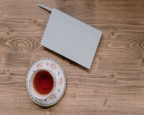 A notebook and a cup of tea on a wooden table