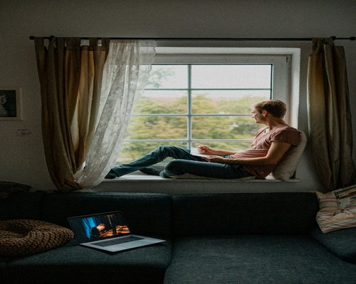 A person taking a break from their laptop to look out the window